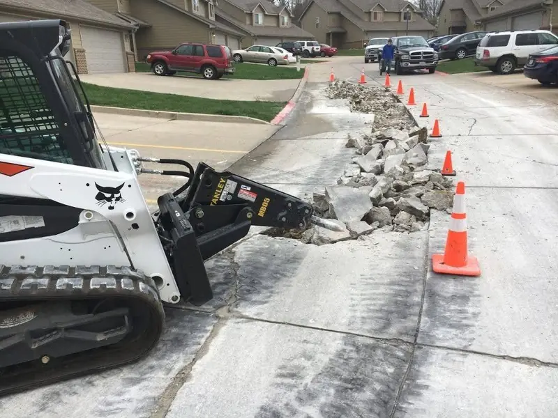 Skid steer breaking out an old concrete driveway for replacement