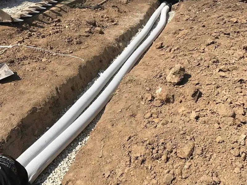 Crew installing drainage pipe in a gravel-bedded trench near St. James, MO
